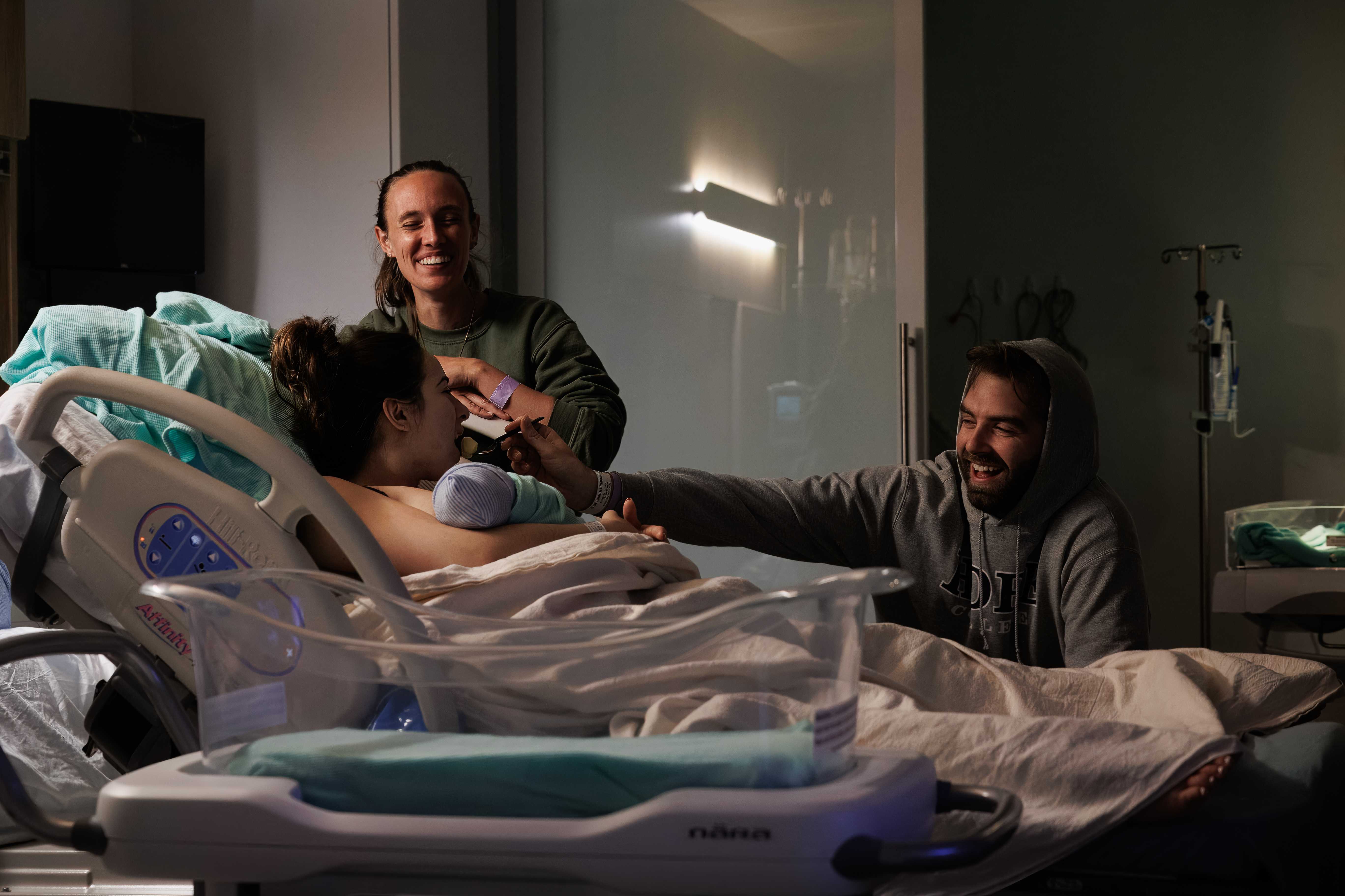 A family laughing together with their doula just after birth