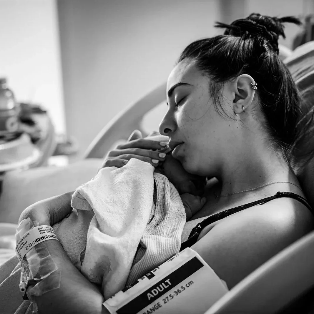 Mother holding her newborn close with partner beside her