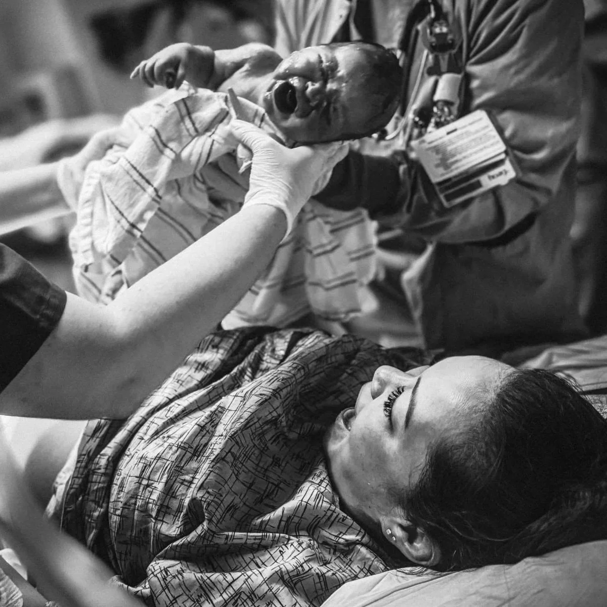 Black and white photo of a newborn lifted just after birth